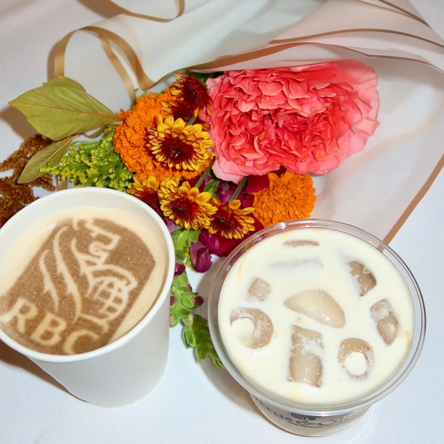 RBC logo printed on the foam of a latte, served beside a bouquet